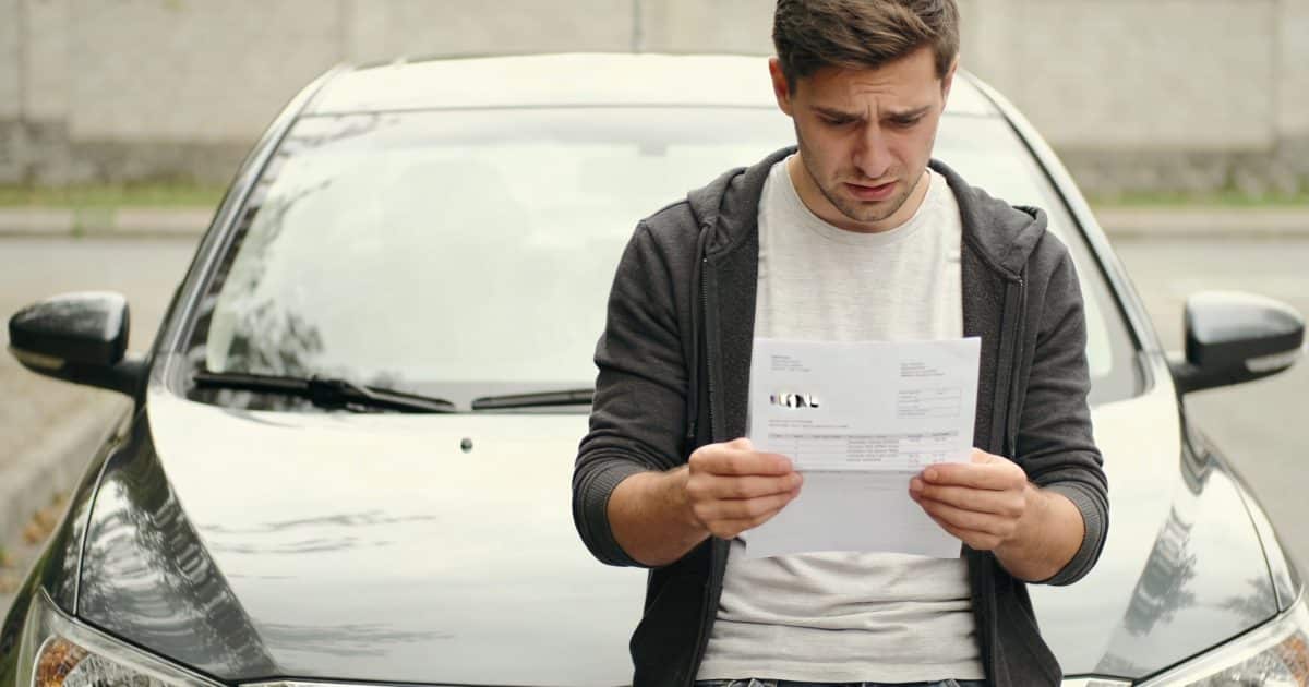 automobiliste inquiete regarde facture elevee devant voiture