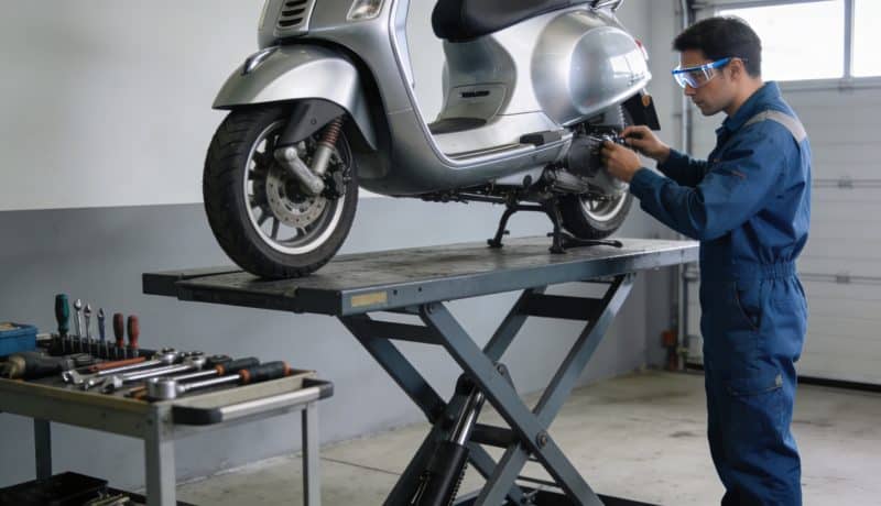 mecanicien inspectant scooter sur pont elevateur en garage