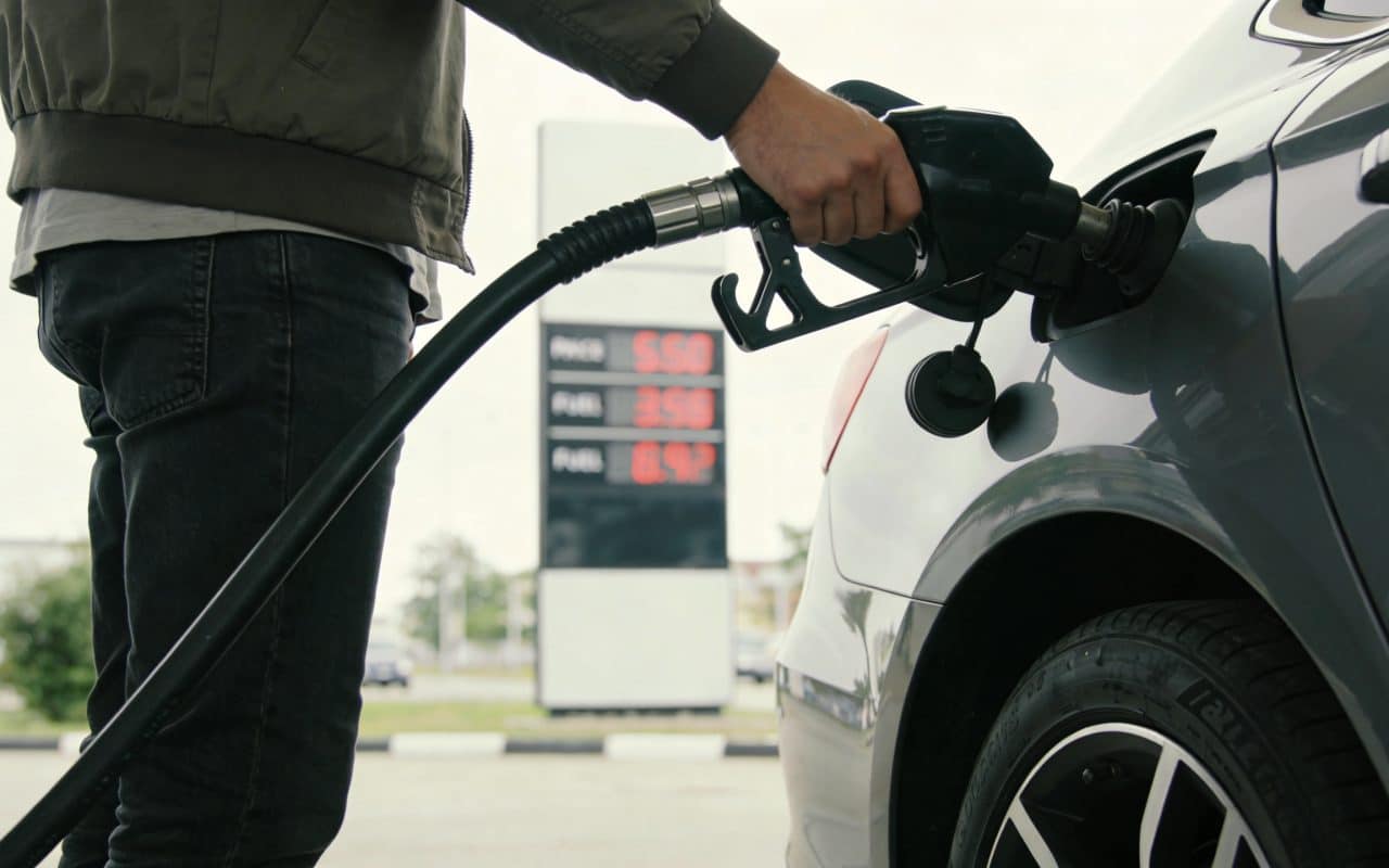 conducteur faisant le plein essence affiche prix station